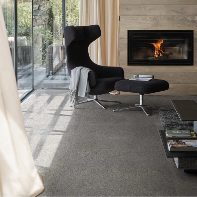 living space featuring large-format, grey fireproof floor tiles paired with a charcoal wingback chair