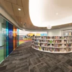 Grey patterned fireproof carpet in a modern curved library space.