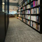 Grey textured fireproof carpet in a modern bookstore or library aisle.