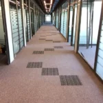 Modern office hallway featuring patterned fireproof carpet tiles.